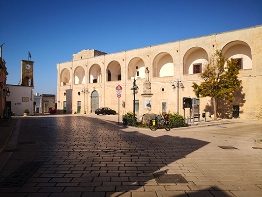 Piazza con orologio e bicicletta a Castiglione d'Otranto